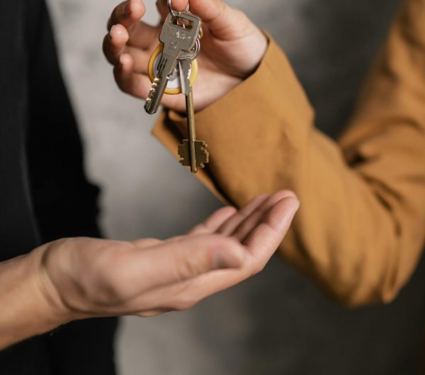 Two adults exchanging house keys, symbolic of property transfer or rental agreement.